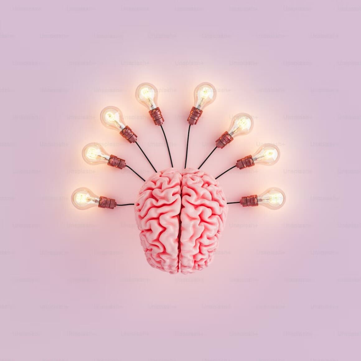  This image features a realistic model of a brain at the center with several lit lightbulbs radiating outward from it, resembling the rays of the sun. The background is a soft pink, creating a bright and creative atmosphere symbolizing ideas, innovation, and brainstorming..